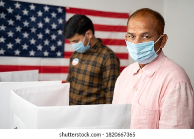 People With Mask Busy At Polling Booth For Voting With US Flag As Background - Concept Of In Person Voting With Covid-19 Safety Measures At Us Election.