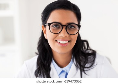 people, medicine, healthcare and facial expression concept - face of happy smiling young doctor or woman in glasses