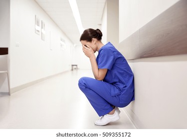 people, medicine, healthcare and sorrow concept - sad or crying female nurse at hospital corridor - Powered by Shutterstock