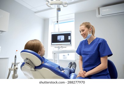 People, Medicine, Stomatology And Health Care Concept - Happy Female Dentist With Patient Girl Talking At Dental Clinic Office