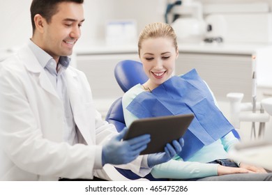 People, Medicine, Stomatology And Health Care Concept - Happy Male Dentist Showing Tablet Pc Computer To Woman Patient At Dental Clinic Office