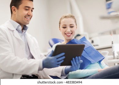 People, Medicine, Stomatology And Health Care Concept - Happy Male Dentist Showing Tablet Pc Computer To Woman Patient At Dental Clinic Office