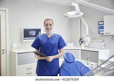 People, Medicine, Stomatology And Healthcare Concept - Happy Young Female Dentist With Tablet Pc Computer At Dental Clinic Office