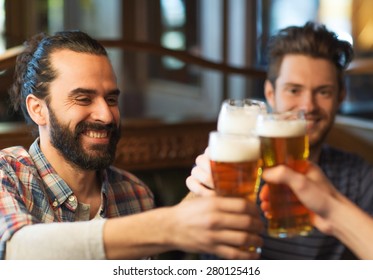 People, Men, Leisure, Friendship And Celebration Concept - Happy Male Friends Drinking Beer And Clinking Glasses At Bar Or Pub