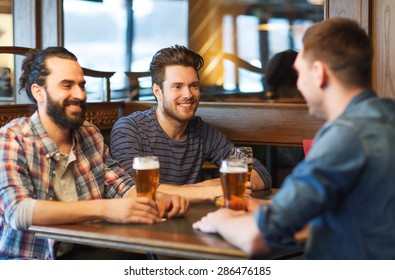 People, Men, Leisure, Friendship And Communication Concept - Happy Male Friends Drinking Beer At Bar Or Pub