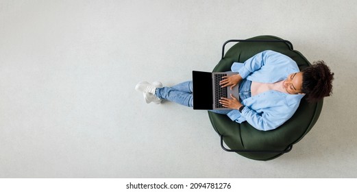 People And Modern Technology. Above Top View Of Young Smiling Black Woman Holding Pc On Lap Sitting On Bean Bag In Living Room, Typing On Keyboard. Cheerful Lady Browsing Internet, Free Copy Space