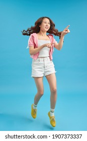 People, Motion And Action Concept - Happy Asian Young Woman Jumping Over Blue