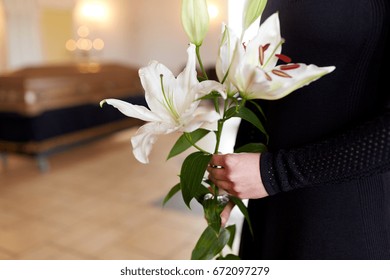 People And Mourning Concept - Close Up Of Woman With White Lily Flowers And Coffin At Funeral In Church