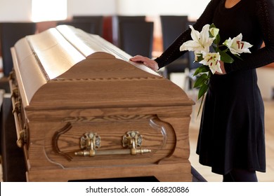 people and mourning concept - woman with white lily flowers and coffin at funeral in church