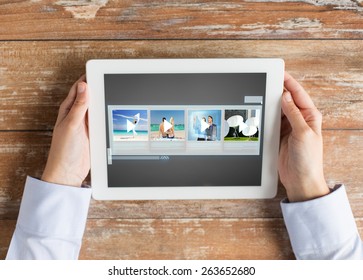 People, Multimedia And Technology Concept - Close Up Of Hands With Video Gallery Slideshow On Tablet Pc At Table