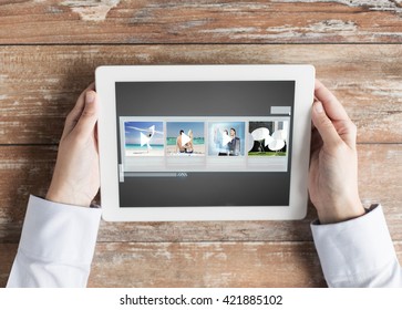 People, Multimedia And Technology Concept - Close Up Of Hands With Video Gallery Slideshow On Tablet Pc At Table