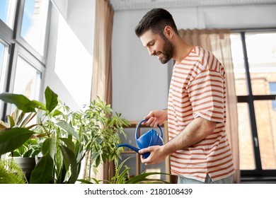 people, nature and plants care concept - happy smiling man watering flowers at home - Powered by Shutterstock