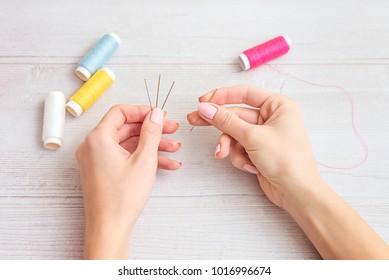 people, needlework, sewing and tailoring concept - tailor woman with thread in needle stitching fabric. Hands sewing with a needle and thread. Fingers pulling thread into the needle - Powered by Shutterstock