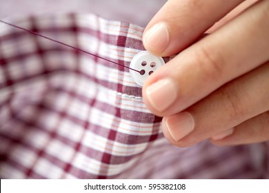 People, Needlework, Sewing And Tailoring Concept - Tailor Woman With Needle Stitching On Button To Shirt