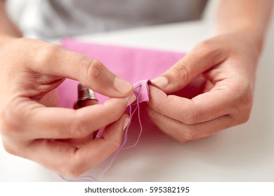 People, Needlework, Sewing And Tailoring Concept - Tailor Woman With Thread In Needle Stitching Fabric Pieces Together