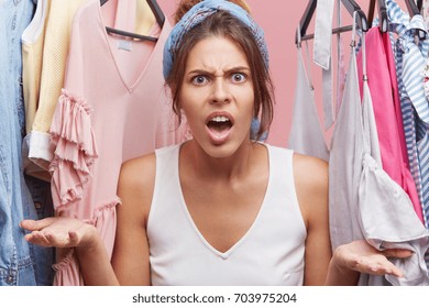 People, negative emotions and facial expressions concept. Angry woman sreaming at seller in clothes shop who serves her very badly. Female shouting while standing in fitting room of clothes shop