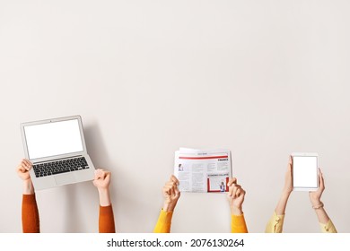 People with newspaper, laptop and tablet computer on light background