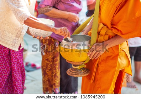 People offering food and things on the alm bowl to Buddhist monks.
