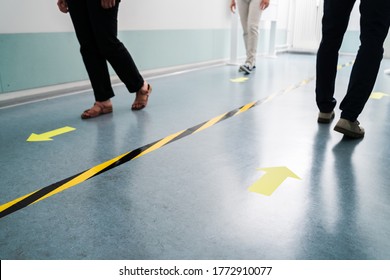 People In Office Following Social Distancing Tape Markings On Floor