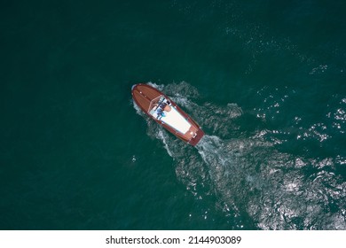 People On An Italian Wooden Boat, Top View. Old Boat On Lake, Italy. Classic Wooden Boat In Motion Drone View.