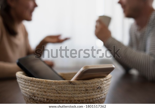 People on meeting without their\
phones. Digital detox concept. Turned off phones putting in\
basket