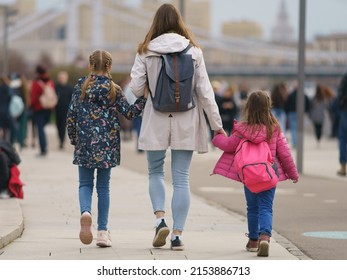 People On The Moscow City Street In Spring Day, They Are Walking. Family Of Young Mother And Two Daughters. Lifestyle Concept. Backs, Rear View. Defocused Background