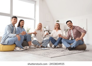 People on poufs holding hands at group therapy session - Powered by Shutterstock