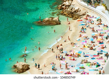people on the sea beach with sunbeds and umbrellas. hot sunny summer day