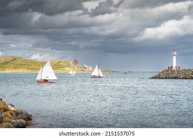 People on a small sailboats exiting Howth marina, passing Howth Lighthouse and per with Irelands Eye island in the background, Dublin, Ireland
