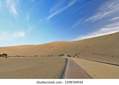 People on Sunday leisure riding sleds down the dunes surrounding Crescent lake-Yueyaquan oasis amidst Singing or Echoing Sand Mountain-Mingsha Shan. Natural wonder of Gobi Desert-Dunhuang-Gansu-China. - Powered by Shutterstock