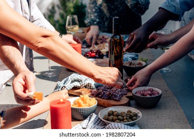 People Outdoor Picking Up Food Appetizer Tapas From A Long Table With A Glass Bottle Of Wine In The Middle. Summer Party Family Gathering.