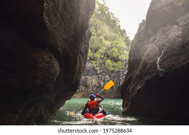 People Paddling The Kayak In Side Cave With Beautiful Sunlight. Kayaking In Sea Between The Rocks.