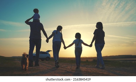 People In The Park. Happy Family A Silhouette Walk At Sunset. Car Travel Kid Dream Concept Sun. Happy Family Parents And Fun Children Walk Silhouette Next To Car. Family Walk Next To Car