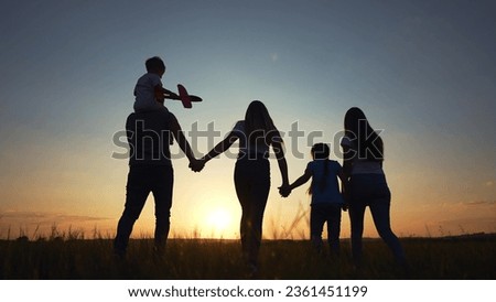 people in the park. happy family silhouette walk at sunset. mom dad and daughters walk holding hands in park. happy family kid dream concept. parents silhouette and children walking back fun
