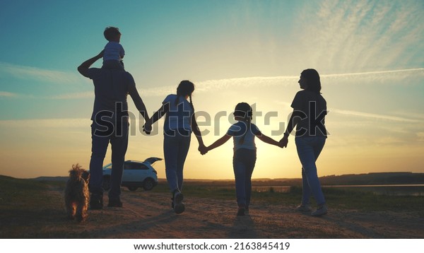 people in\
the park. happy family a silhouette walk at sunset. car travel kid\
dream concept sun. happy family parents and fun children walk\
silhouette next to car. family walk next to\
car
