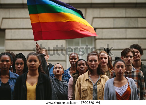 People\
participate in the pride parade. Multi-ethnic people in the city\
street with a woman waving gay rainbow\
flag.