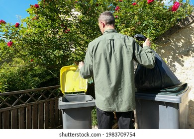 People performing a selective sorting of household waste in recycling bins. Man putting plastic bottles in a yellow container and garbage in a bag in a green container.	