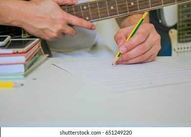 People play guitar and write notes on the table.