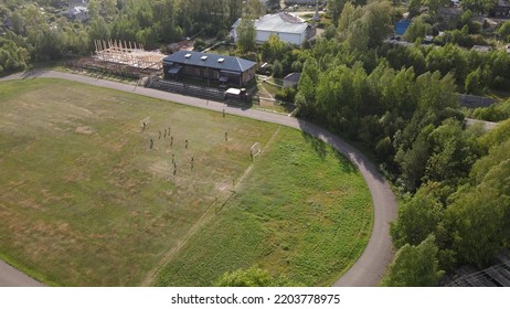 People Playing Football On Green Field In Village