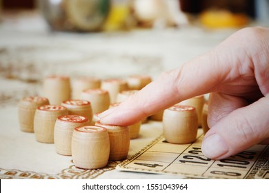 People Playing Lotto Game. Closeup Of Old People's Fingers. Board Game Lotto Or Bingo. Wooden Lotto Barrels With Numbers Lying On Lotto Cards.