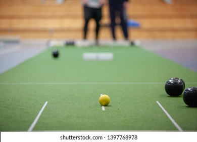 People Playing The Sport Bowls On An Indoor Mat