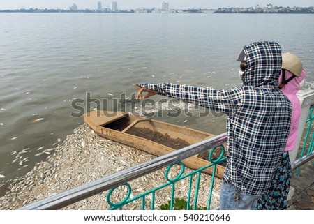 People pointing to mass dead fish on lake in Hanoi