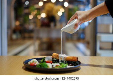 People Are Pouring Cream Sauce On. Salmon Fish Steak In Black Plate