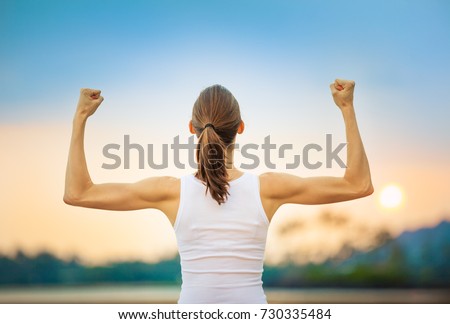 People, power, strength, and determination.  Strong woman flexing her muscles against sunset.  Foto stock © 