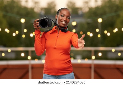 people, profession and photography concept - happy young woman with digital camera giving her hand for handshake over garland lights on roof top party background - Powered by Shutterstock