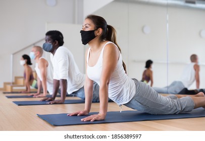 People in protective masks practice yoga in the gym - Powered by Shutterstock