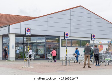 People With Protective Masks Queuing Outside A Supermarket Due To The Covid-19 Coronavirus Which Obliges Customers To Quota Admissions