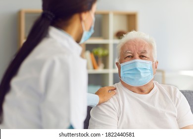 People In Protective Masks. Woman Doctor Visits The Elderly Man And Provides Him With Support And Talks To Him During The Quarantine. Nurse Visits A Man Who Is At Risk.