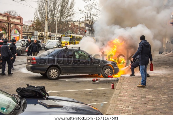 People put out a burning car. Fire on the\
street. Odessa City, Ukraine, 25 November\
2019