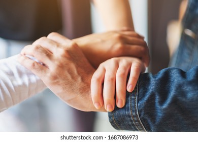 People putting their hands in a circle together for unity and teamwork concept - Shutterstock ID 1687086973